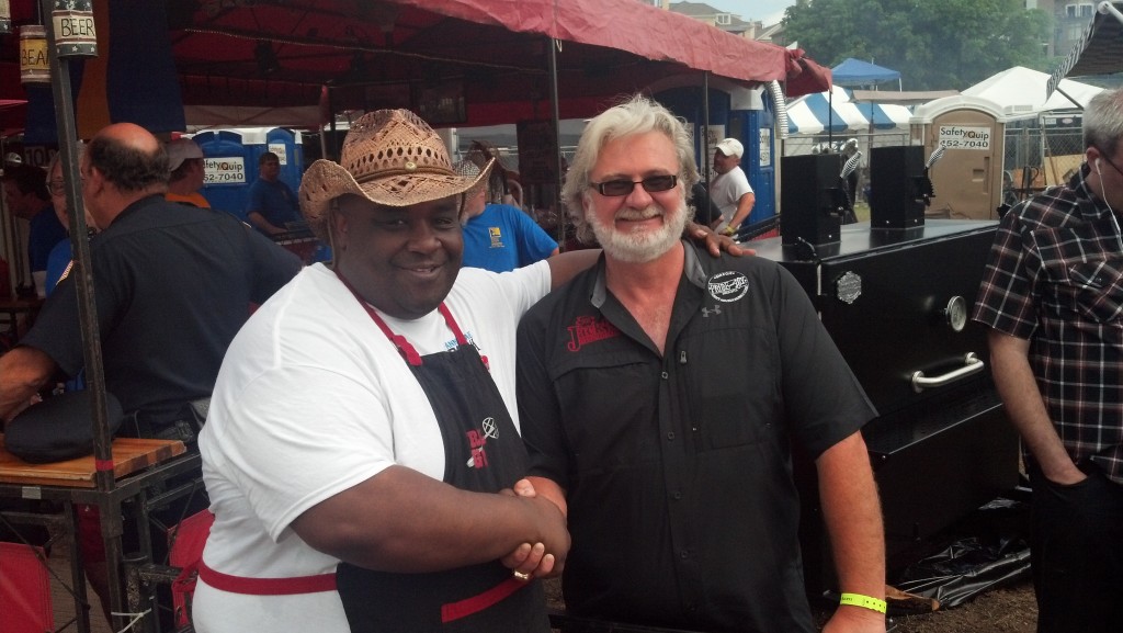Two men shaking hands at outdoor event.