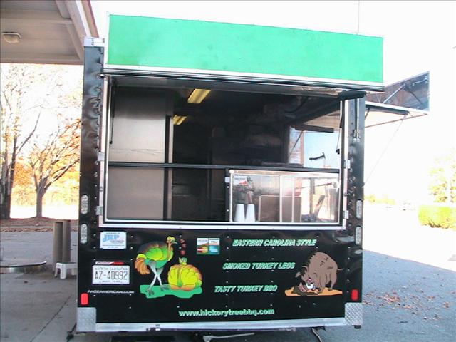 Black food truck with green signage and cartoon burger logo.